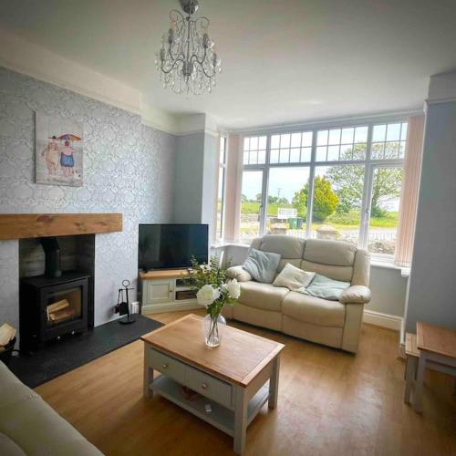 a living room with a couch and a table at Coastal walks, Log burner & Hot tub in Llangadwaladr