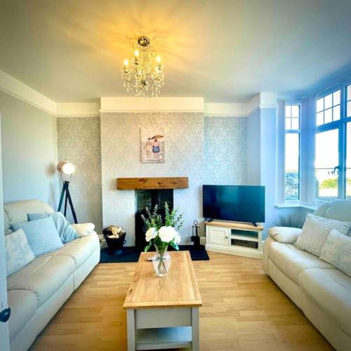 a living room with a couch and a tv at Coastal walks, Log burner & Hot tub in Llangadwaladr
