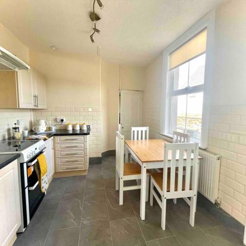 a kitchen with a table and a table and chairs at Coastal walks, Log burner & Hot tub in Llangadwaladr