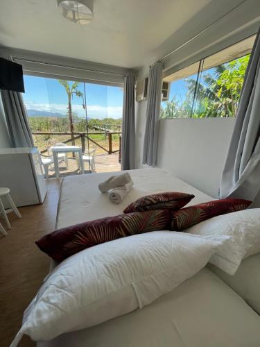 a large white bed with pillows and a large window at Pousada Las Ondas in Garopaba