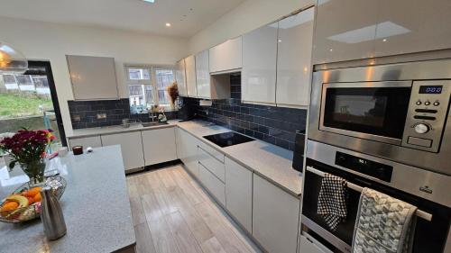 a kitchen with white cabinets and a stove top oven at Cosy Studio Wembley Stadium Gem in Wembley