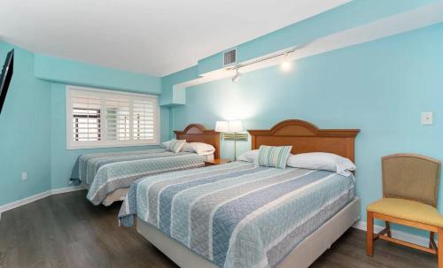 2 Betten in einem Zimmer mit blauen Wänden und einem Stuhl in der Unterkunft 4800 S Ocean Blvd, 0915 - Ocean Front Sleeps 6 in Myrtle Beach
