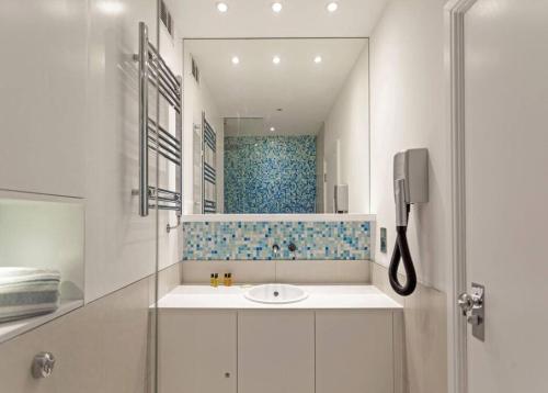 Baño blanco con lavabo y espejo en Shirlock Home - Italianflat, en Londres