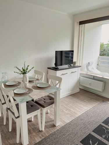 comedor con mesa con sillas y TV en Strandnahe Wohnung mit Meerblick, en Sierksdorf