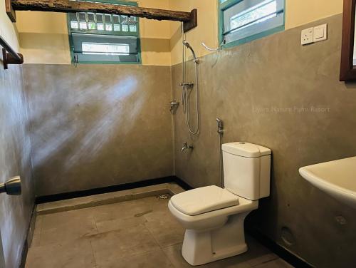 een badkamer met een toilet, een douche en een wastafel bij Liyara Nature Farm Resort in Gampaha