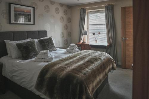 Un dormitorio con una cama grande y una ventana en The Steadings, Aviemore Luxury 5 star rated 3 Bed with home cinema garden and parking, en Aviemore