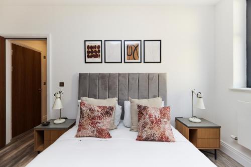 a bedroom with a white bed with red pillows at The Wembley Escape - Lovely 2BDR Flat in London