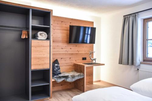 a bedroom with a wooden wall with a tv at Landhaus Bernhard in Holzgau