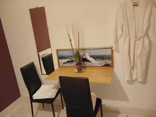 a dining room with a table and two chairs and a robe at PARADIS CHAMBRES D'HÔTES PROCHE PARIS - AÉROPORT CHARLES DE GAULLE AIRPORT - PARC DES EXPOSITION VILLEPINTE - DYSNAYLAND PARIS. in Tremblay En France