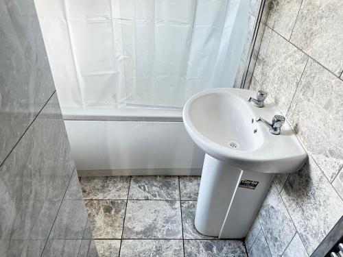 a white sink in a bathroom with a shower at Ebehi Inn in London