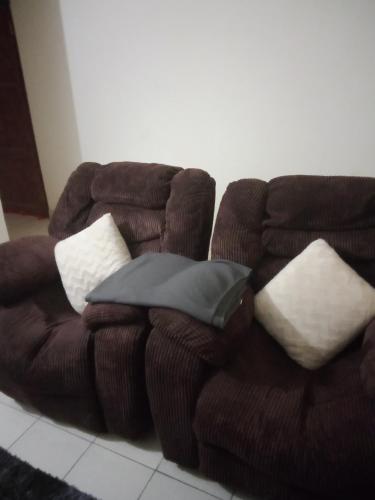 - un canapé brun avec des oreillers dans l'établissement Victoria apartments, à Mtwapa