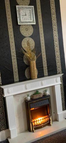a fireplace with a clock on top of it at Apartment Bradford in Bradford