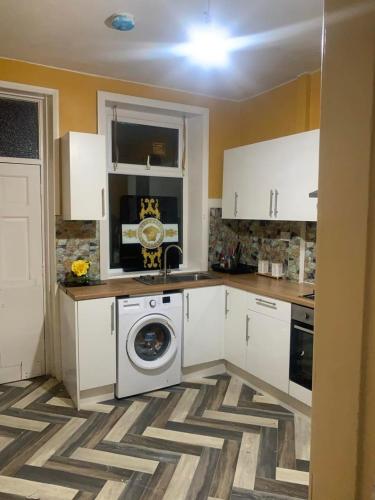 a kitchen with white cabinets and a washing machine at Apartment Bradford in Bradford