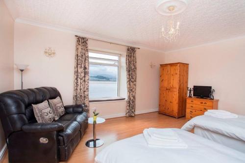 a living room with a leather couch and a window at Sea Front Spacious Apartment on Anglesey in Brynsiencyn