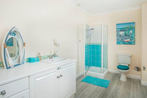 a bathroom with a sink and a toilet and a shower at Sea Front Spacious Apartment on Anglesey in Brynsiencyn