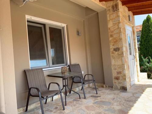 a patio with two chairs and a table and a window at Petrino Apartments in Kavala