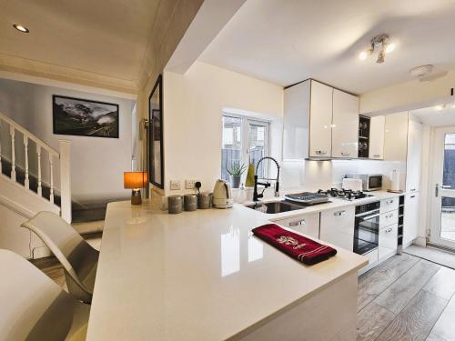 a white kitchen with a large white counter top at MAGICAL HARRY POTTER THEMED HOME IN WATFORD - FREE off-street PARKING in Watford