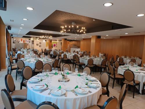 un salón de banquetes con mesas y sillas blancas en Valcarce Ferrol, en Narón