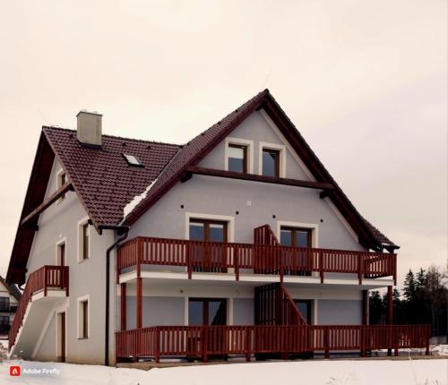 duży biały dom z drewnianym balkonem w obiekcie Apartmány Louka w mieście Vaclavov u Bruntalu