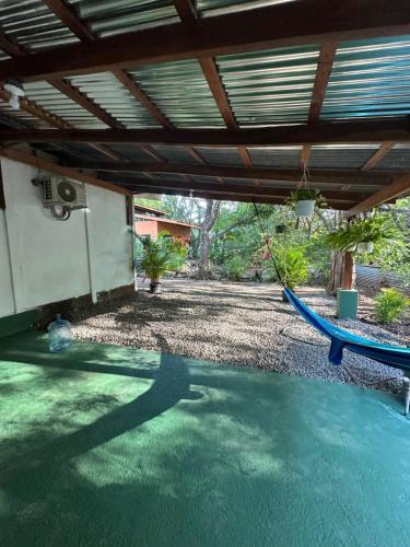 a patio with a blue hammock in a yard at Aldo’s place #2 in Playa Negra
