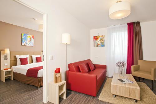 een hotelkamer met een bed en een rode stoel bij Residhome Nanterre La Défense in Nanterre