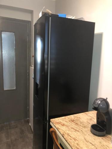 a black refrigerator in a kitchen with a counter at Beauvais chambre 1 in Beauvais