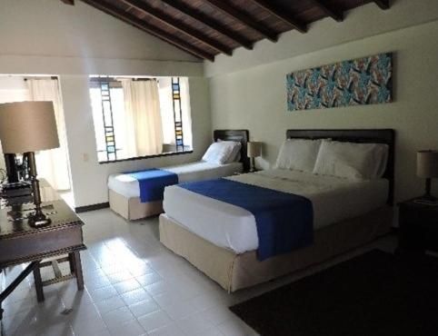ein Schlafzimmer mit 2 Betten und einem Tisch mit einer Lampe in der Unterkunft Hotel Acuarela in La Granja