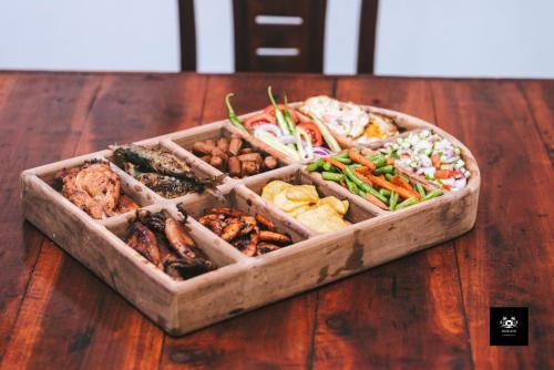 a wooden table with a tray of different types of food at BAWANS VILLA Holiday Home for Family or Group in Hikkaduwa