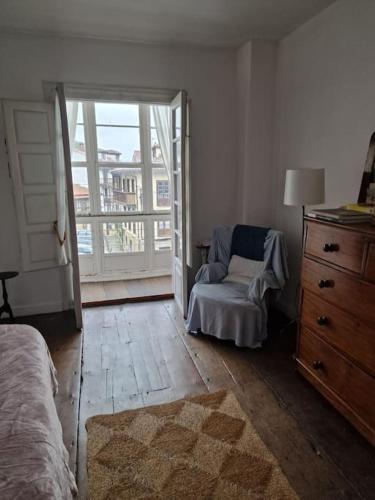 a bedroom with a bed and a chair and a window at Mima's House · La Casa de Mima in Comillas