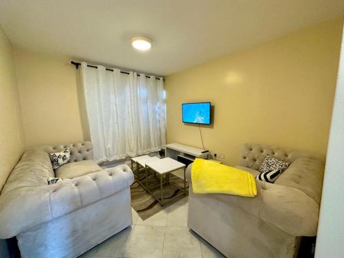 a living room with two couches and a tv at Candy's Staycation in Thika