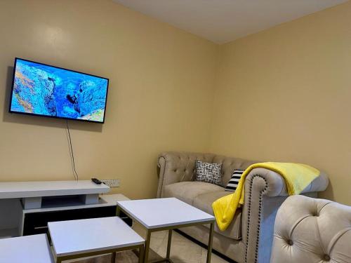 sala de estar con sofá y TV de pantalla plana en Candy's Staycation en Thika