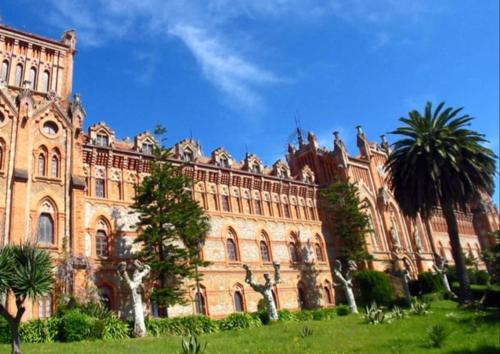 a large building with palm trees in front of it at Mima's House · La Casa de Mima in Comillas