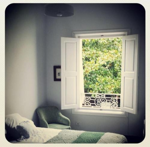 a bedroom with a window and a bed and a chair at Mima's House · La Casa de Mima in Comillas