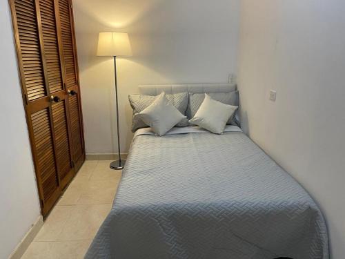 Un dormitorio con una cama azul con almohadas y una lámpara en Apartamento Buenos Aires Medellin en Medellín
