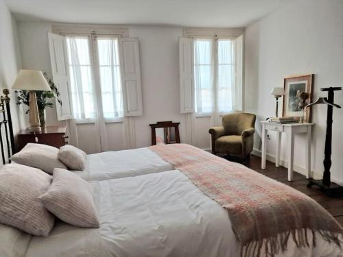 a bedroom with a large white bed and windows at Mima's House · La Casa de Mima in Comillas