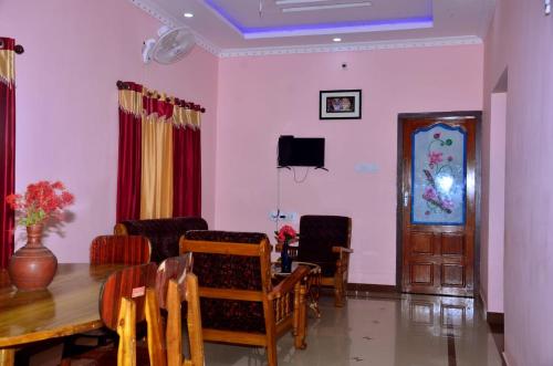 a dining room with a table and chairs and a tv at Bhaskar villas homestays in Varkala