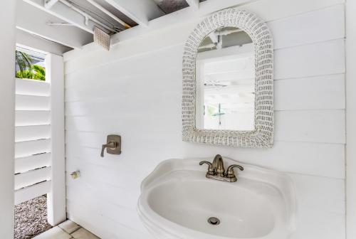 een witte badkamer met een wastafel en een spiegel bij Seaside Manor in Bradenton Beach