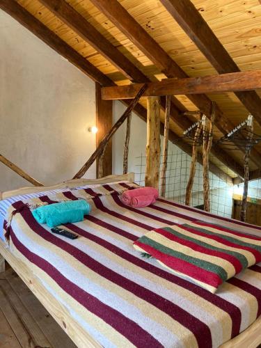 Una cama con una manta de rayas de colores. en Cabaña Cercana al Centro en El Bolsón