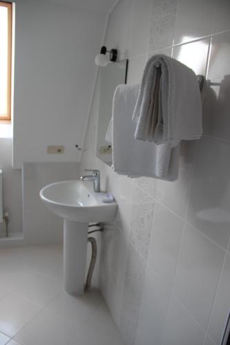 a white bathroom with a sink and a towel at Mіnі Gotel Pozitiv in Horodets'ke