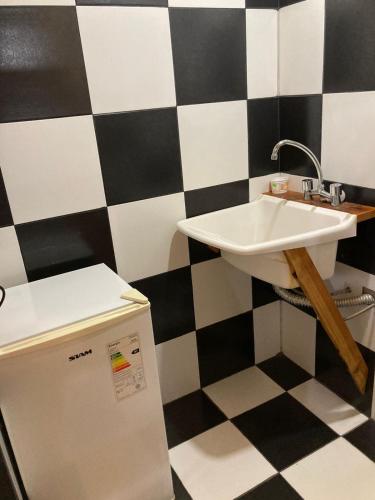 baño con lavabo y pared a cuadros en blanco y negro. en Cabaña Cercana al Centro en El Bolsón