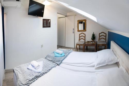 a bedroom with a white bed with a tv on the wall at Guest House Ćiro in Sarajevo