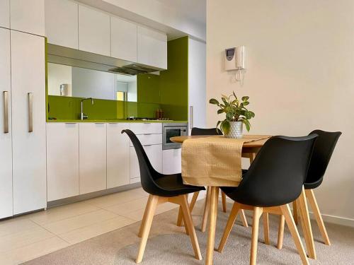 a kitchen with a wooden table and black chairs at Lovely 1BR Apartment - Free Parking in Melbourne