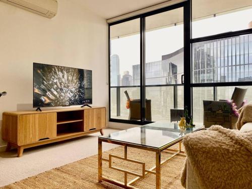 a living room with a tv and a glass table at Lovely 1BR Apartment - Free Parking in Melbourne