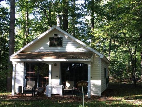a small white house with chairs in the yard at Quiet cottage on wooded property in Lusby