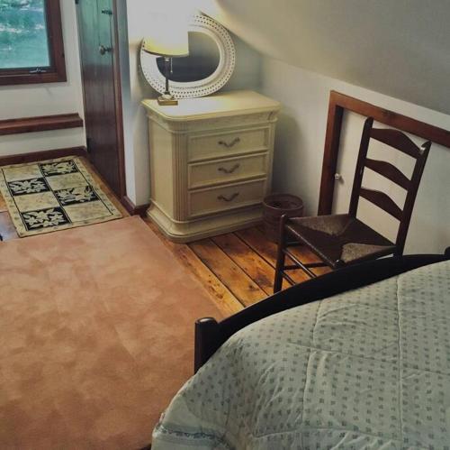 ein Schlafzimmer mit einer Kommode, einem Stuhl und einem Spiegel in der Unterkunft Quiet cottage on wooded property in Lusby