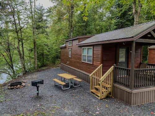 a cabin in the woods with a picnic table and a grill at HTR Adirondacks in Old Forge