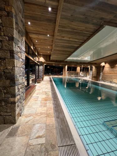 a swimming pool in a building with a wooden ceiling at Les Cornettes in La Chapelle-dʼAbondance