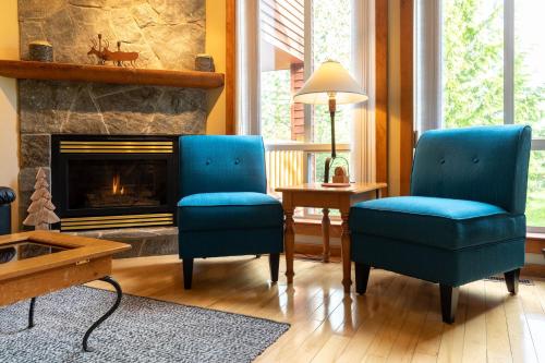 twee blauwe stoelen in een woonkamer met een open haard bij Polar Peak by Fernie Central Reservations in Fernie