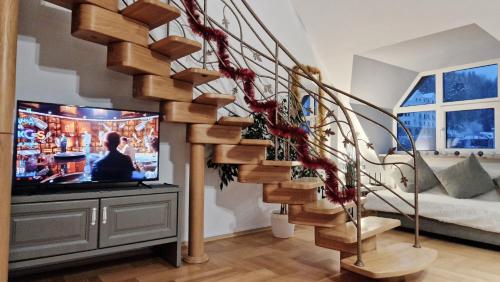 a living room with a spiral staircase and a tv at Apartament Gwiazda 503 in Krynica Zdrój