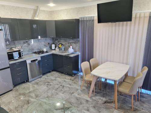 a kitchen with blue cabinets and a table and chairs at Lotus Guesthouse in Fatʼmayy